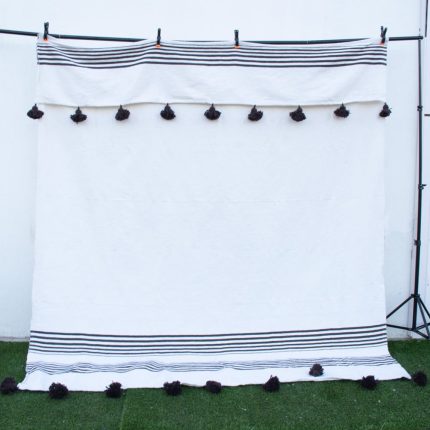 Manta blanca con lineas negras y pompones negros