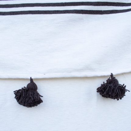 Manta blanca con lineas negras y pompones negros