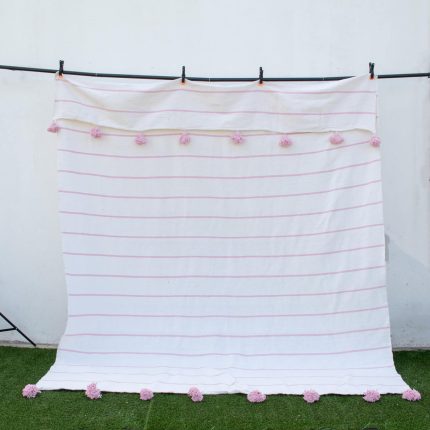 Manta blanca con lineas y pompones rosadas