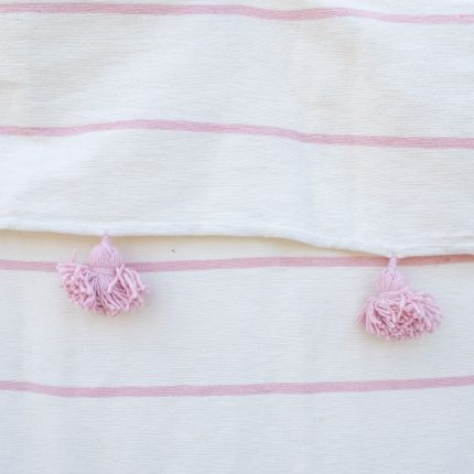 Manta blanca con lineas y pompones rosadas