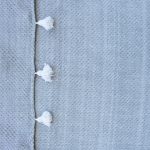 Manta gris con rombos y pompones blancos
