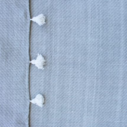Manta gris con rombos y pompones blancos